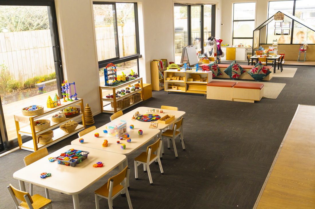 Sunlit corner of the Morepork room with playhouse and cushions