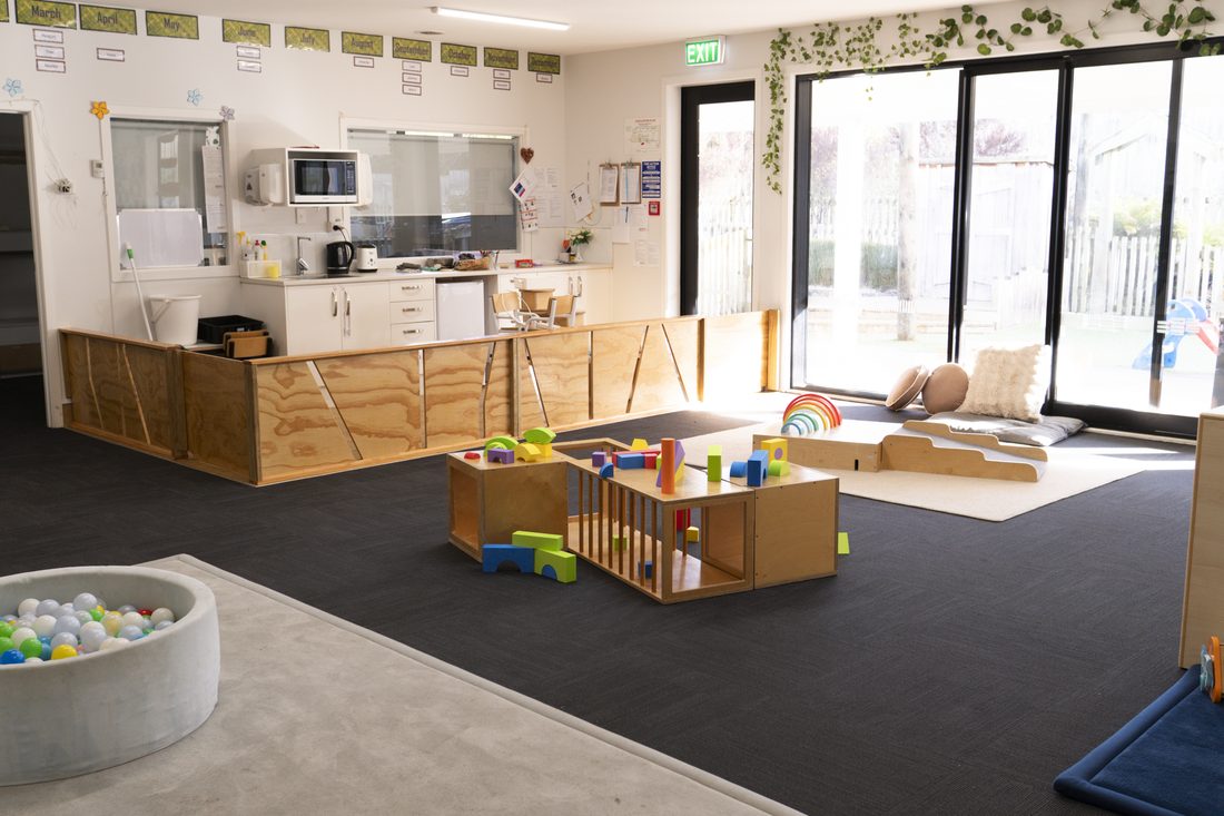 Low wooden partitions and calm play spaces in the Nest room