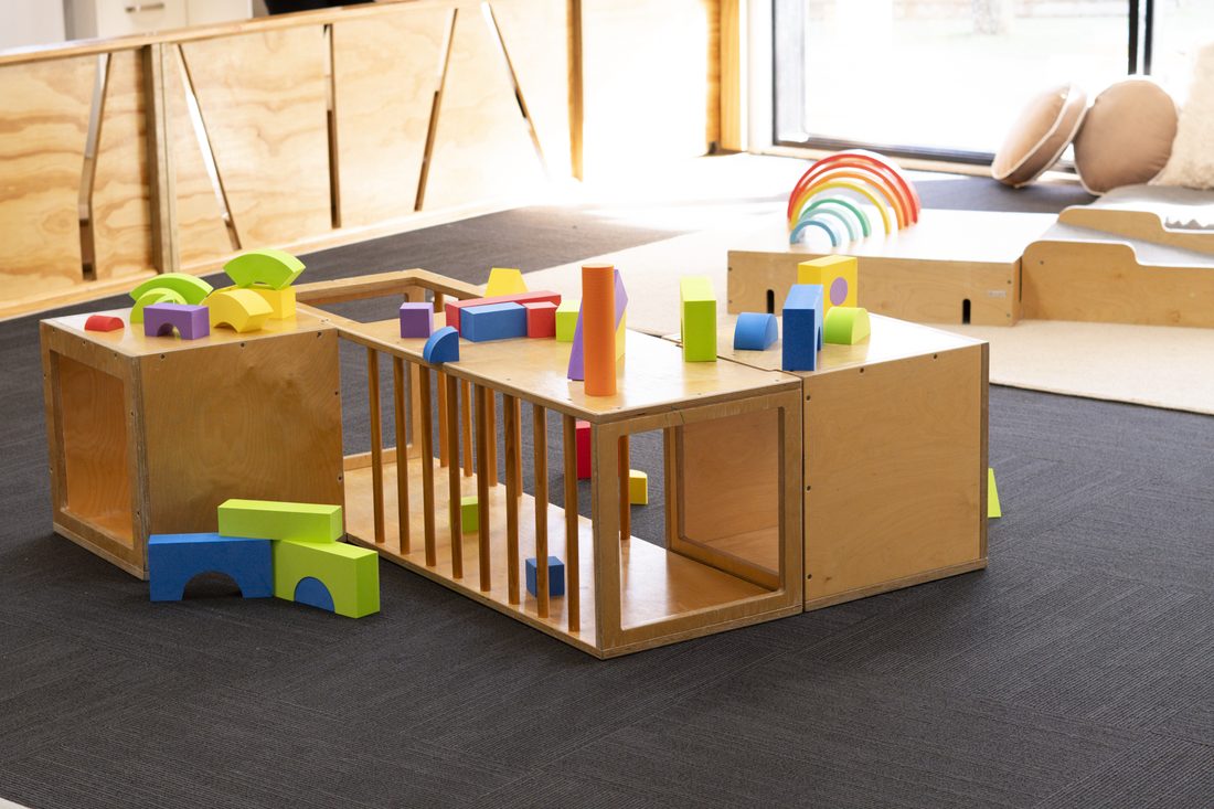 Rainbow stacking toys and soft blocks on a low table in the Nest