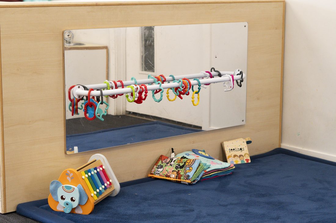 Mirror wall with hanging sensory toys in the Nest room